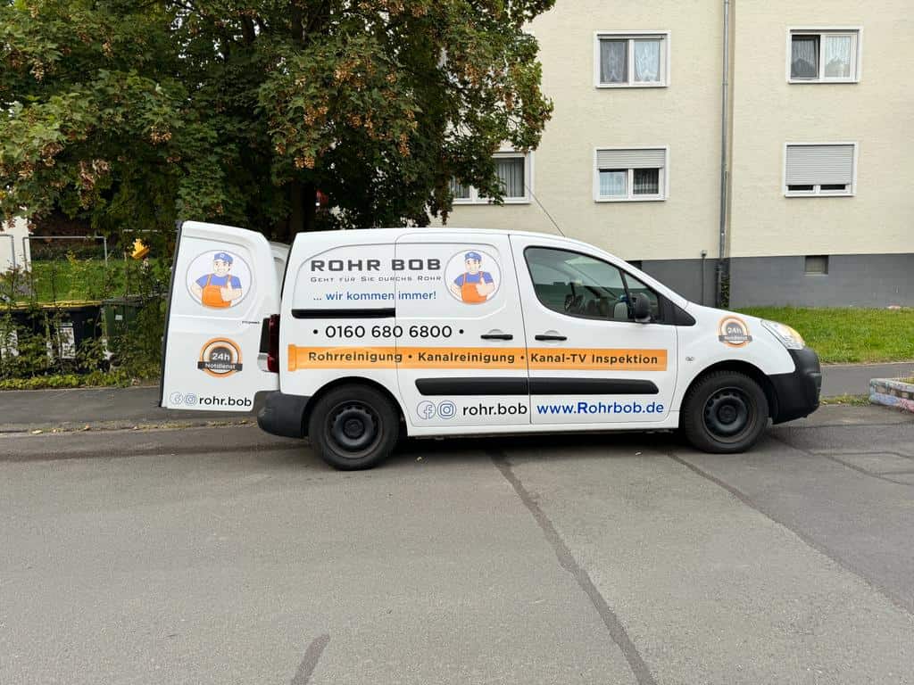 Rohrreinigungsfahrzeug von RohrBob mit geöffneter Hintertür bei einem Einsatz vor einem Gebäude in Gießen